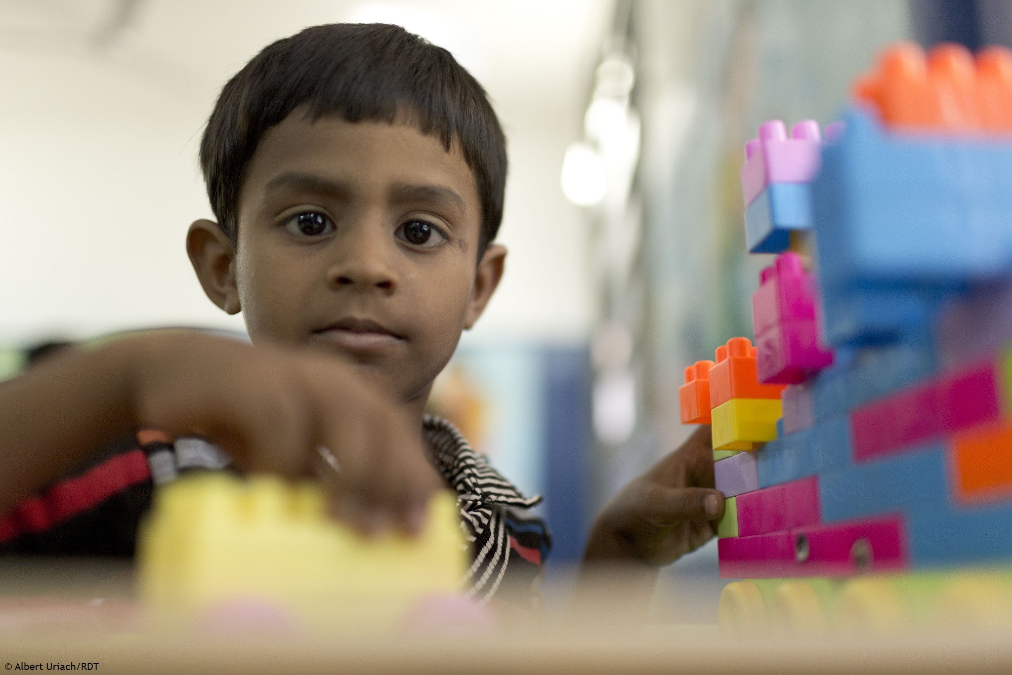 Kind mit Behinderung in Indien: Ein Kind baut mit bunten Bauklötzen.