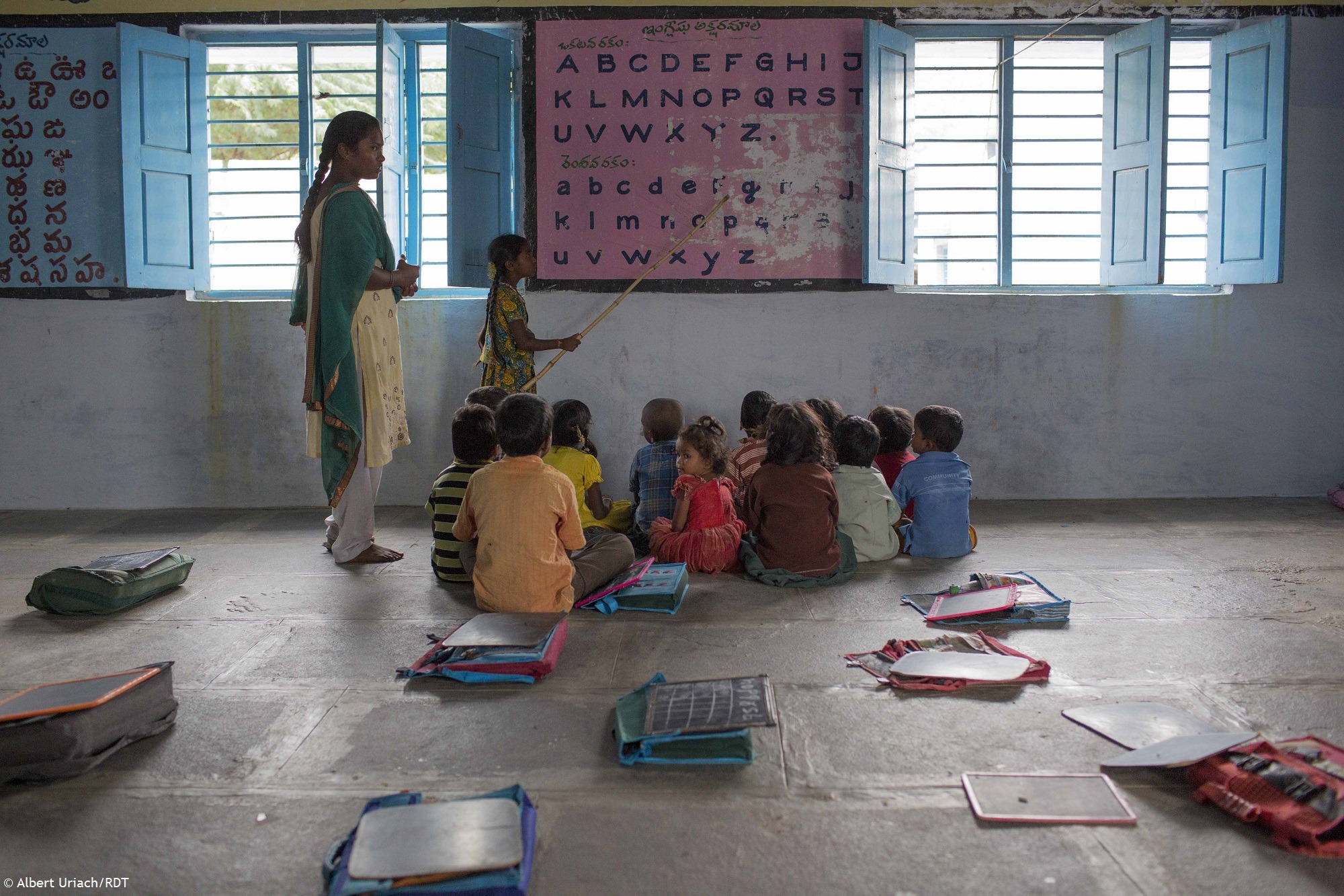 Kinder sitzen in einer Schule in Indien und schauen sich das Alphabet auf einer Wandtafel an. Bildung Indien
