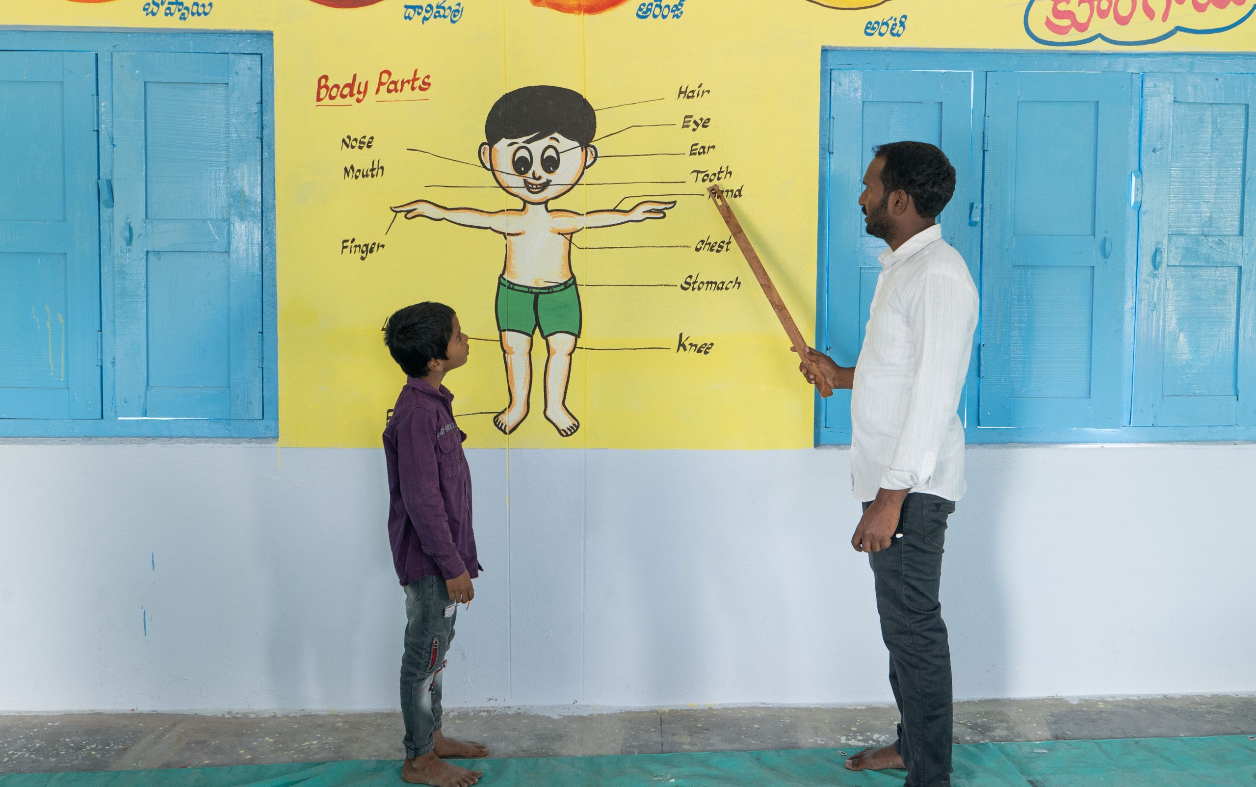 Lehrer und Schulkind an einer Wandtafel in einer Stiftungsschule in Indien. Alphabetisierung in Indien fördern