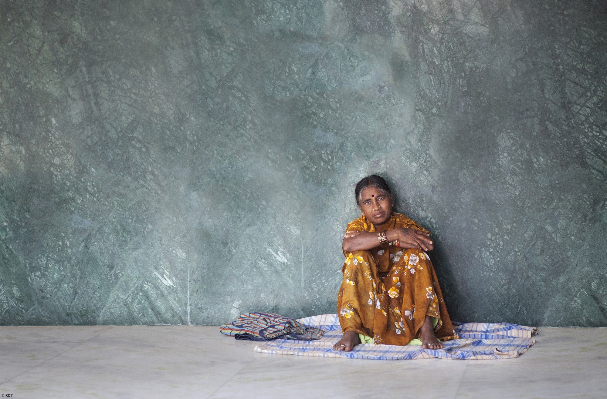 Frau sitzt auf dem Boden vor einer Wand in Indien. Hilfe bei Gewalt gegen Frauen in Indien