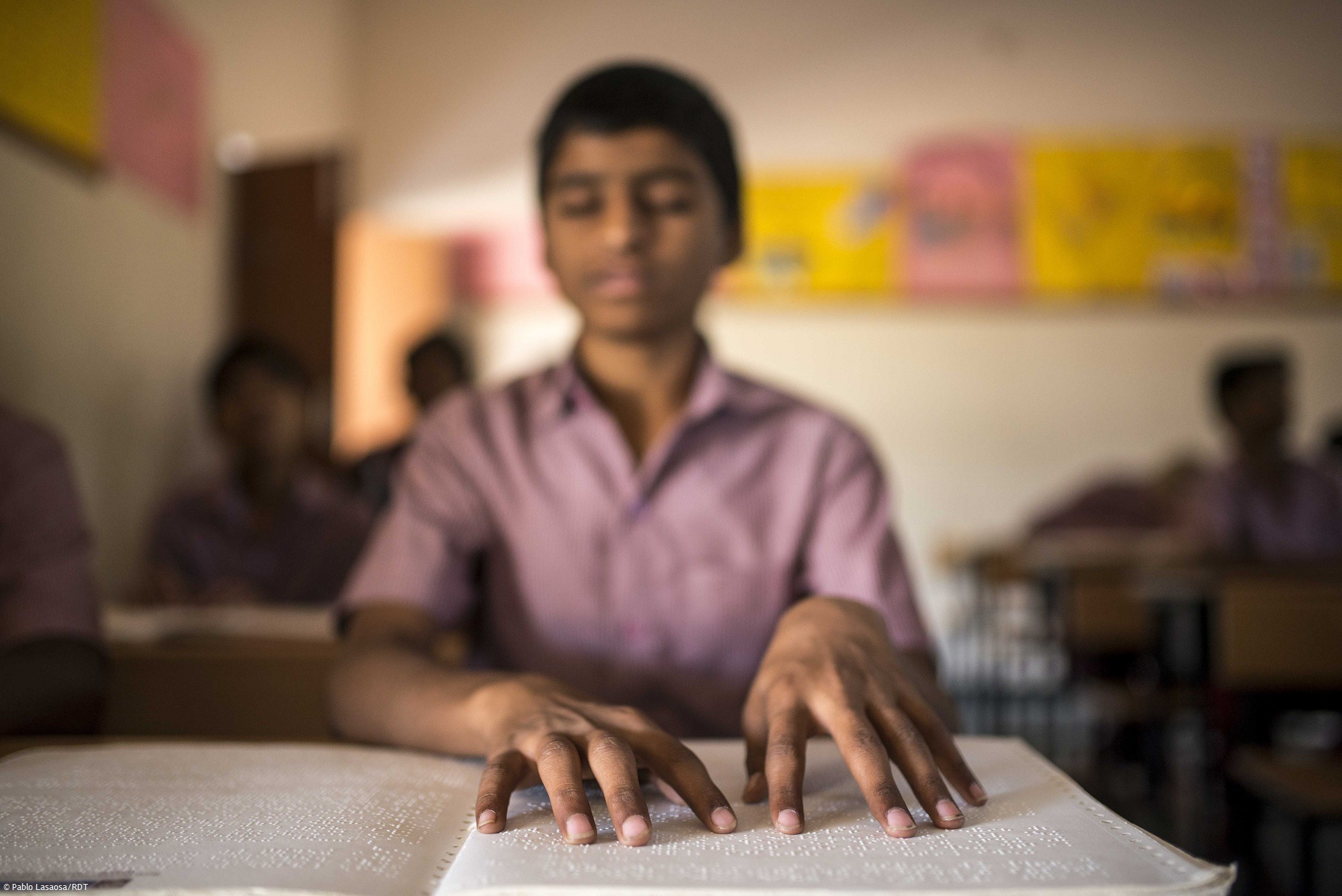 Junge liest in Buch mit Braille-Schrift. Inklusion Behinderung - Kindern mit Behinderung Bildung und Teilhabe ermöglichen.