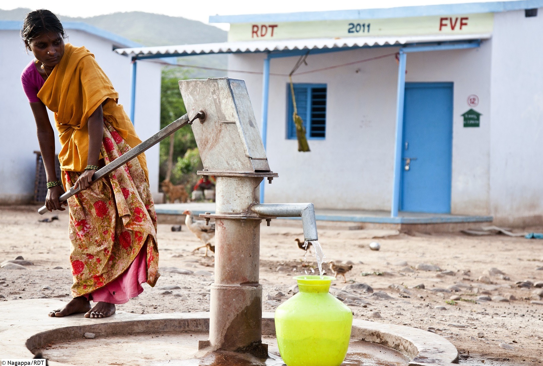 Indien Infrastruktur: Frau an Brunnen füllt sauberes Trinkwasser in Behälter